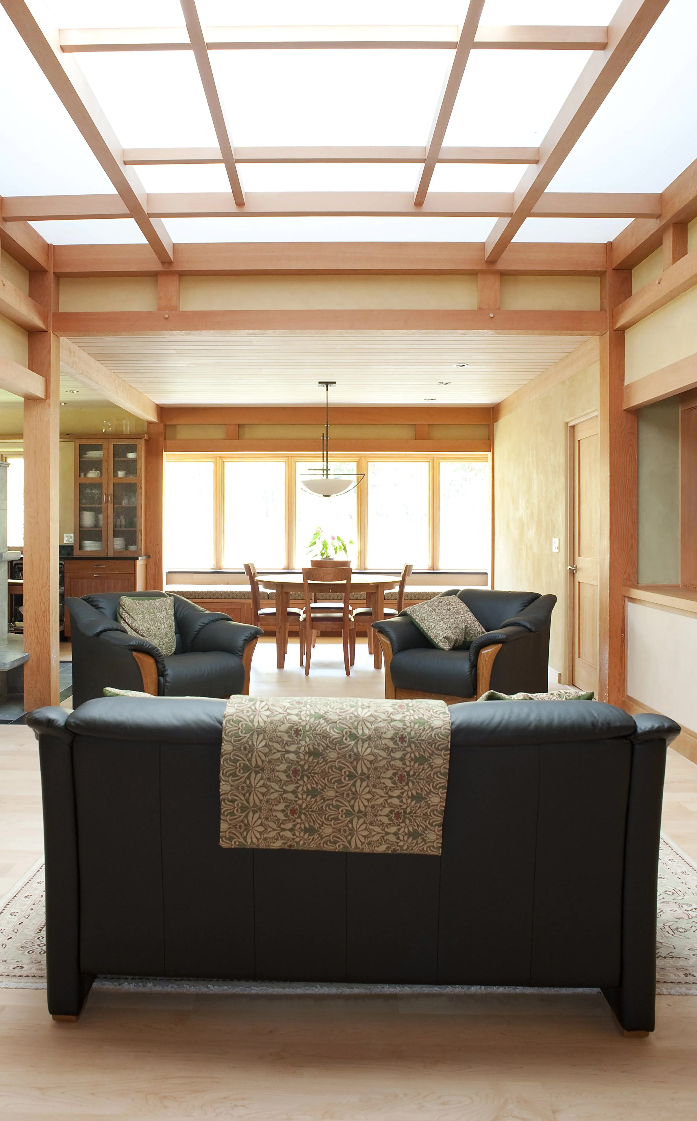 Living room of the Baker-Laporte residence in Ashland Oregon with timber frame, gridded skylight ceiling, natural plaster walls, and view to dining nook