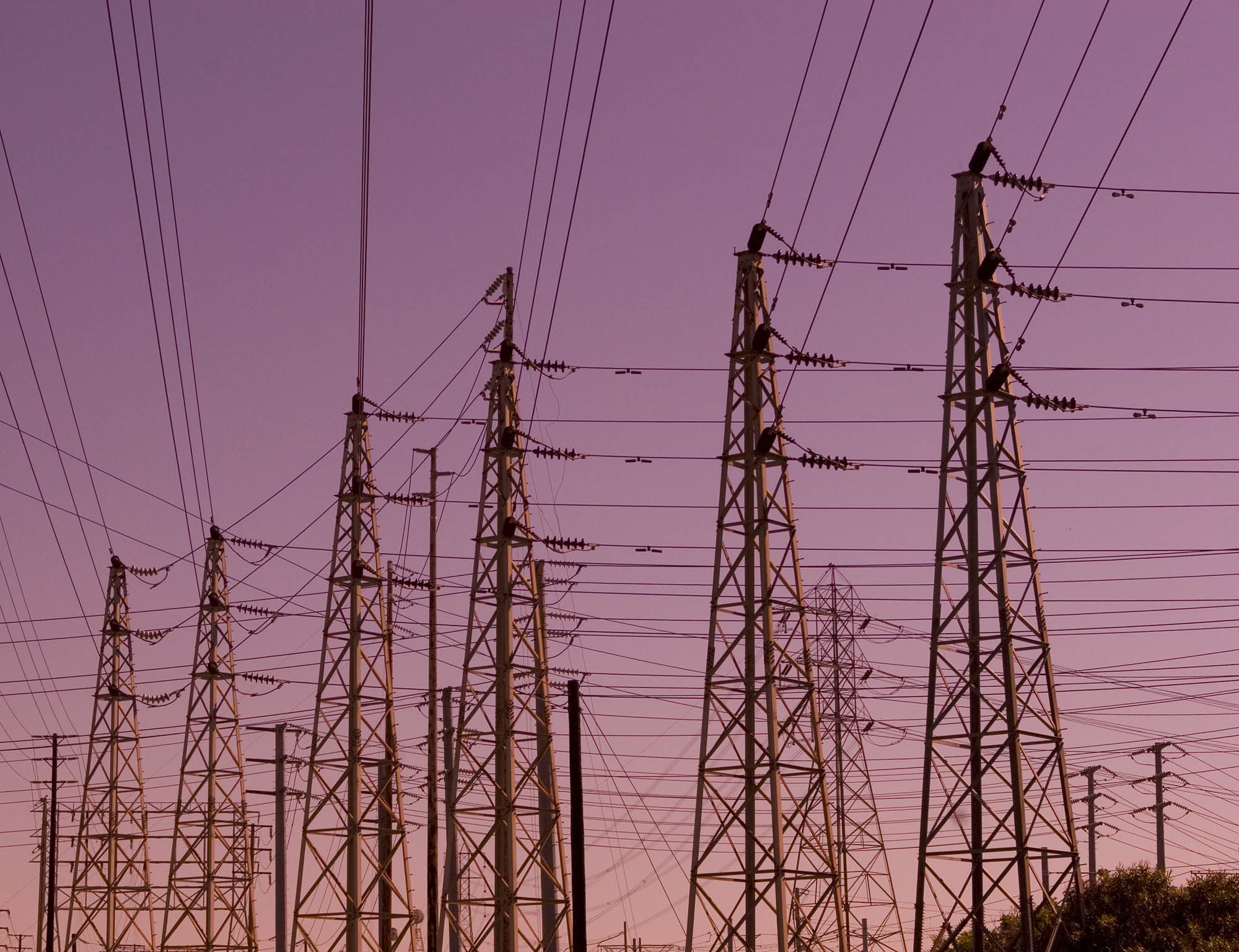 Silhouette of electrical transmission towers against a pink-purple dusk sky