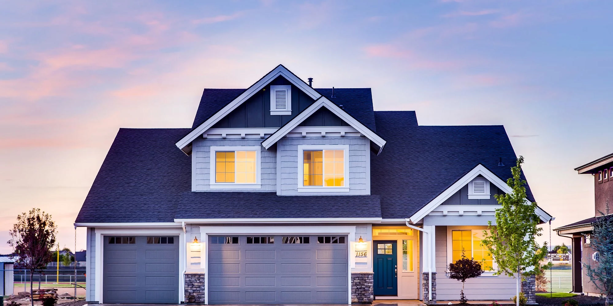 Two-story Craftsman home at dusk with warm yellow window light