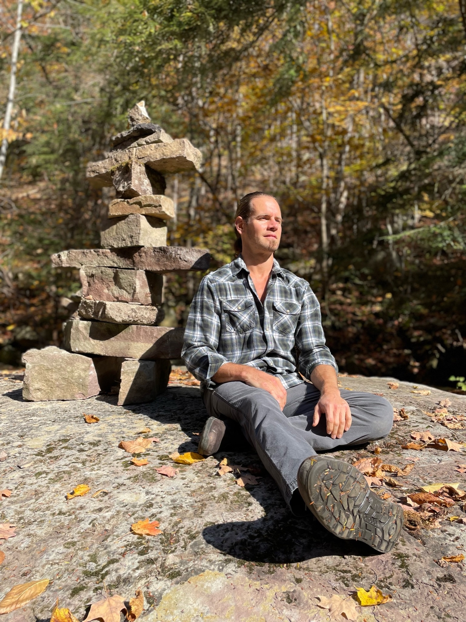 Roman Shapoval — Building Biology Advocate seated by inukshuk cairn in autumn forest