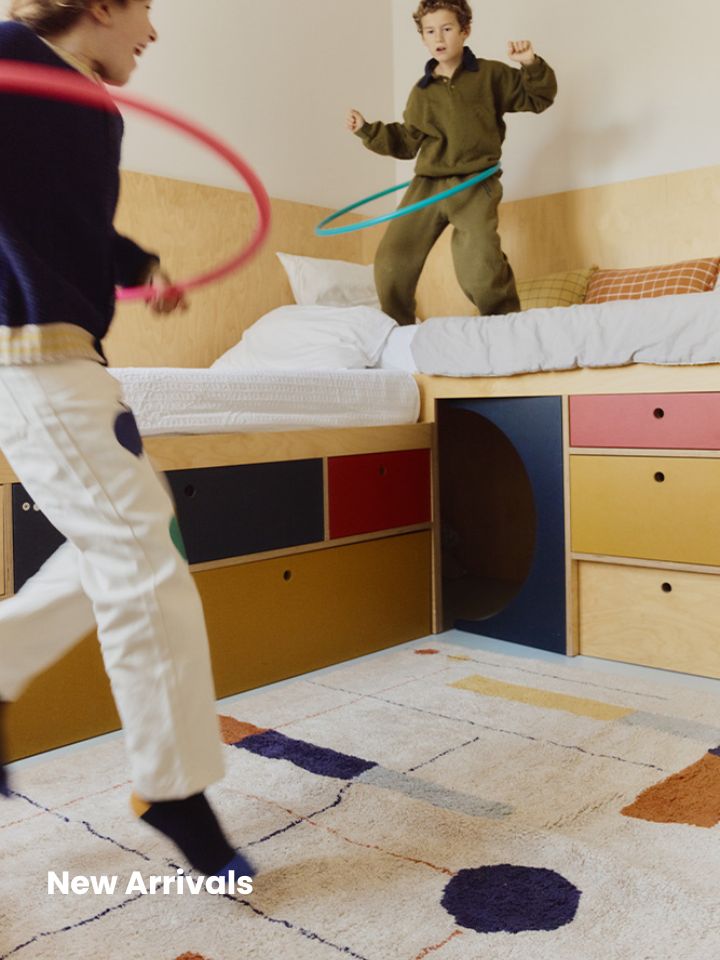 Two children playing with hula hoops in a kids' room with a Rugs by Roo washable rug