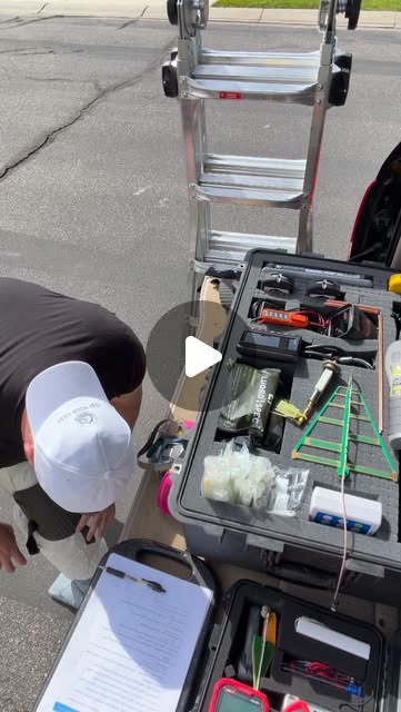 Mason in branded cap with open equipment case of EMF meters and testing instruments