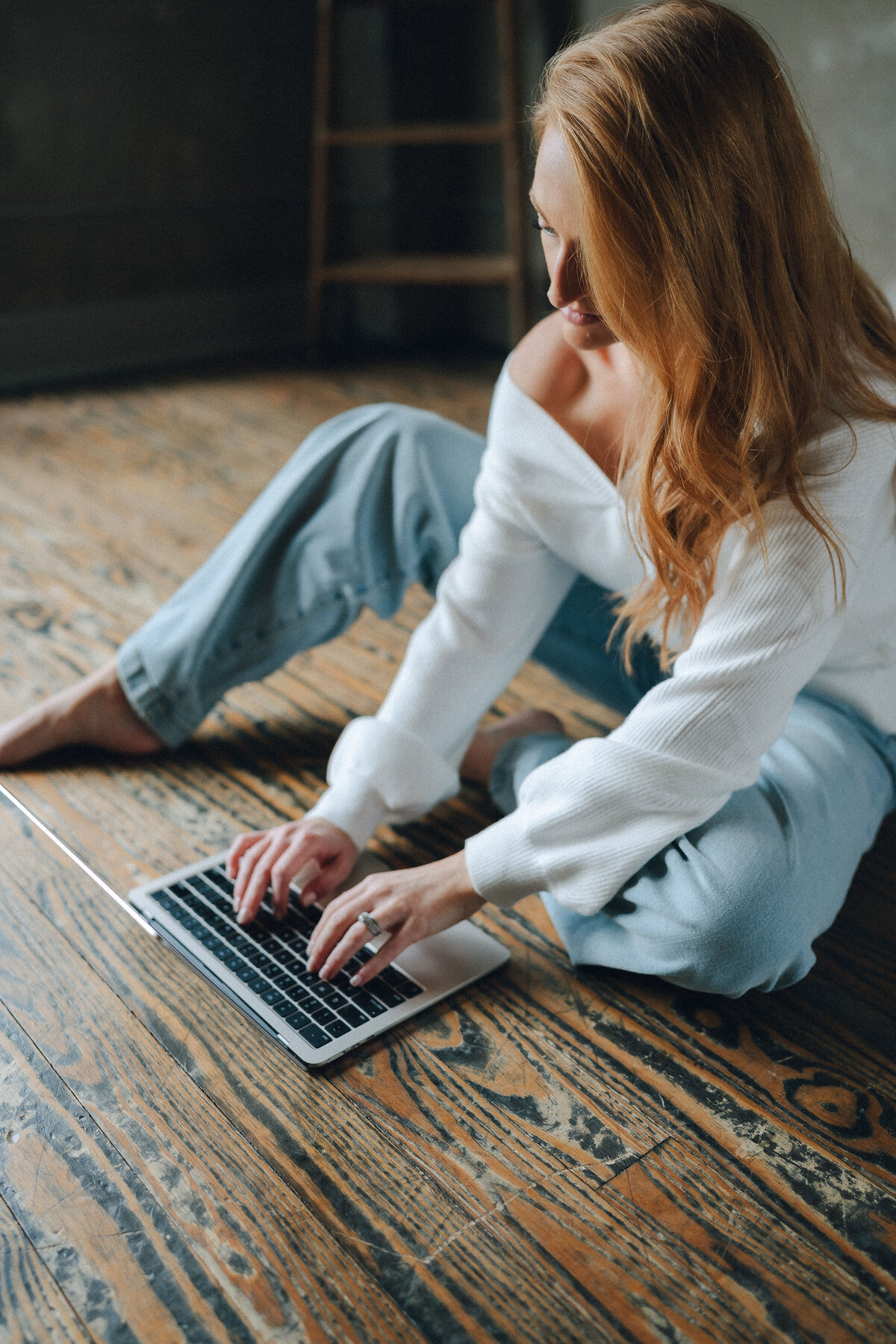 Lauren on floor with laptop, moody editorial lighting